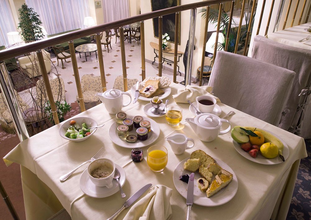 Завтрак, включающий фрукты, выпечку и чай, сервирован на столике с видом на балкон и обеденную зону.