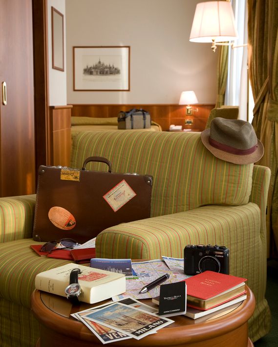В гостиничном номере стояло кресло в зеленую полоску, на котором лежали чемодан и шляпа, а на небольшом столике — книги, фотоаппарат и карты.