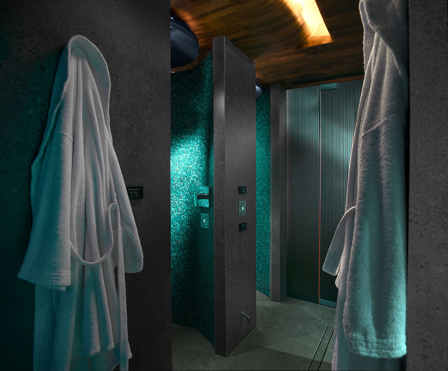两件白色浴袍挂在深色纹理墙面上，两侧是现代化的淋浴区，淋浴区的墙壁是闪亮的蓝绿色鹅卵石瓷砖。
