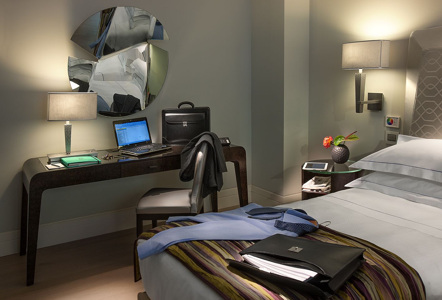 В гостиничном номере стоял деревянный стол с ноутбуком, стул, а на кровати лежала черная сумка с одеждой.