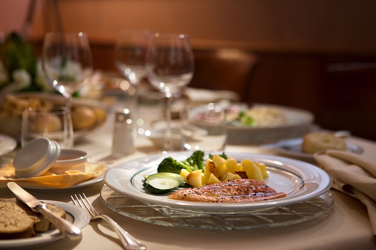 Блюдо из рыбы, картофеля и брокколи, поданное на тарелке на сервированном для ужина столе.