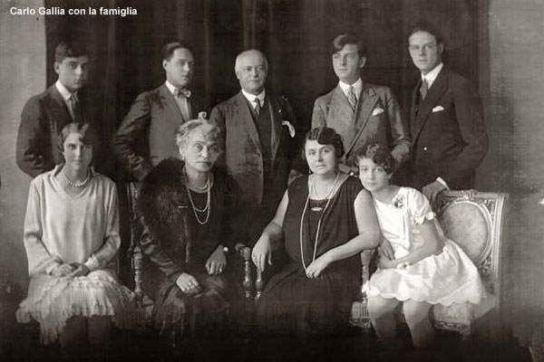 一张复古的黑白影楼合影，照片中一家九口身着正式服装合影。