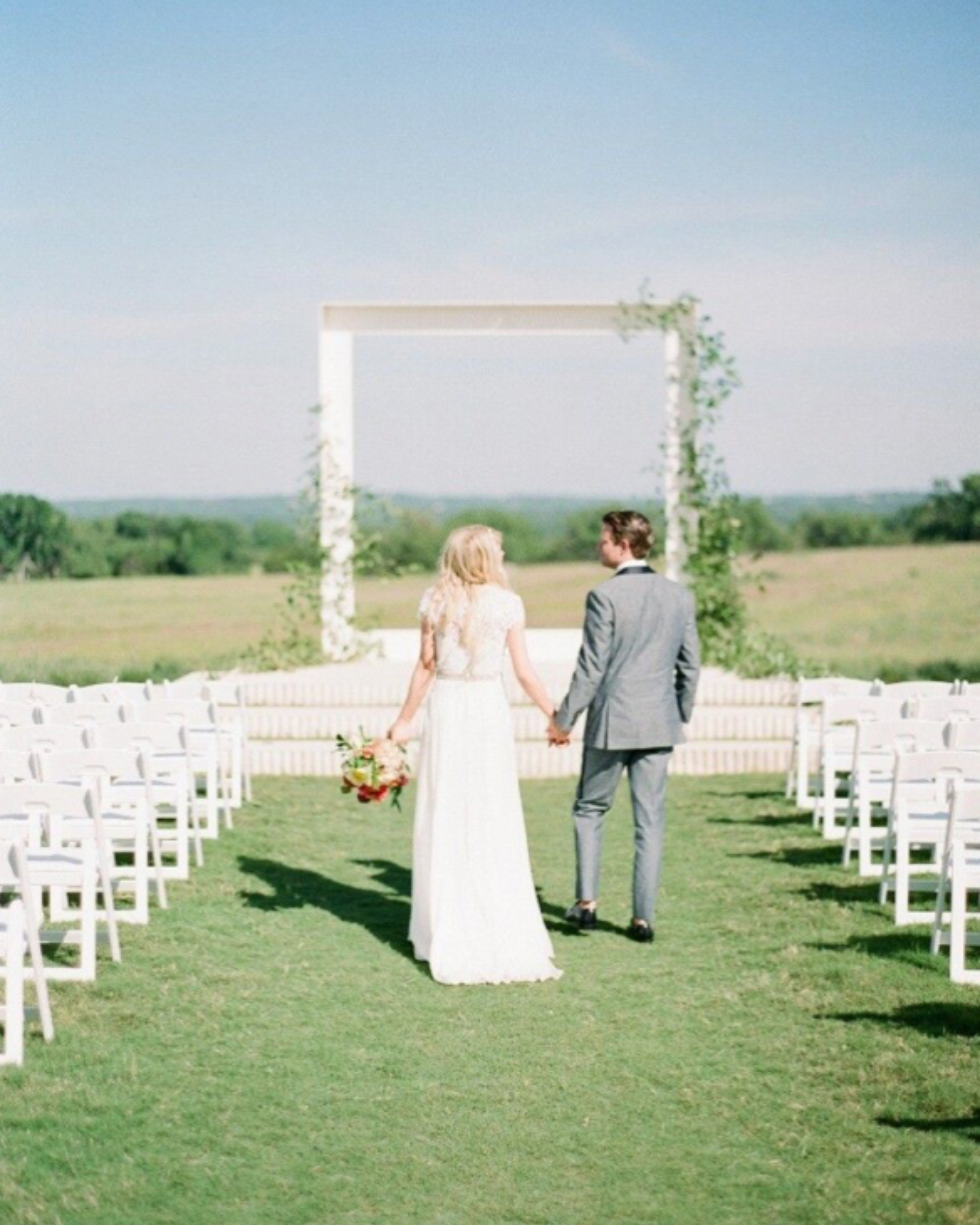 A bride and groom are holding hands while walking down the aisle at their wedding ceremony.