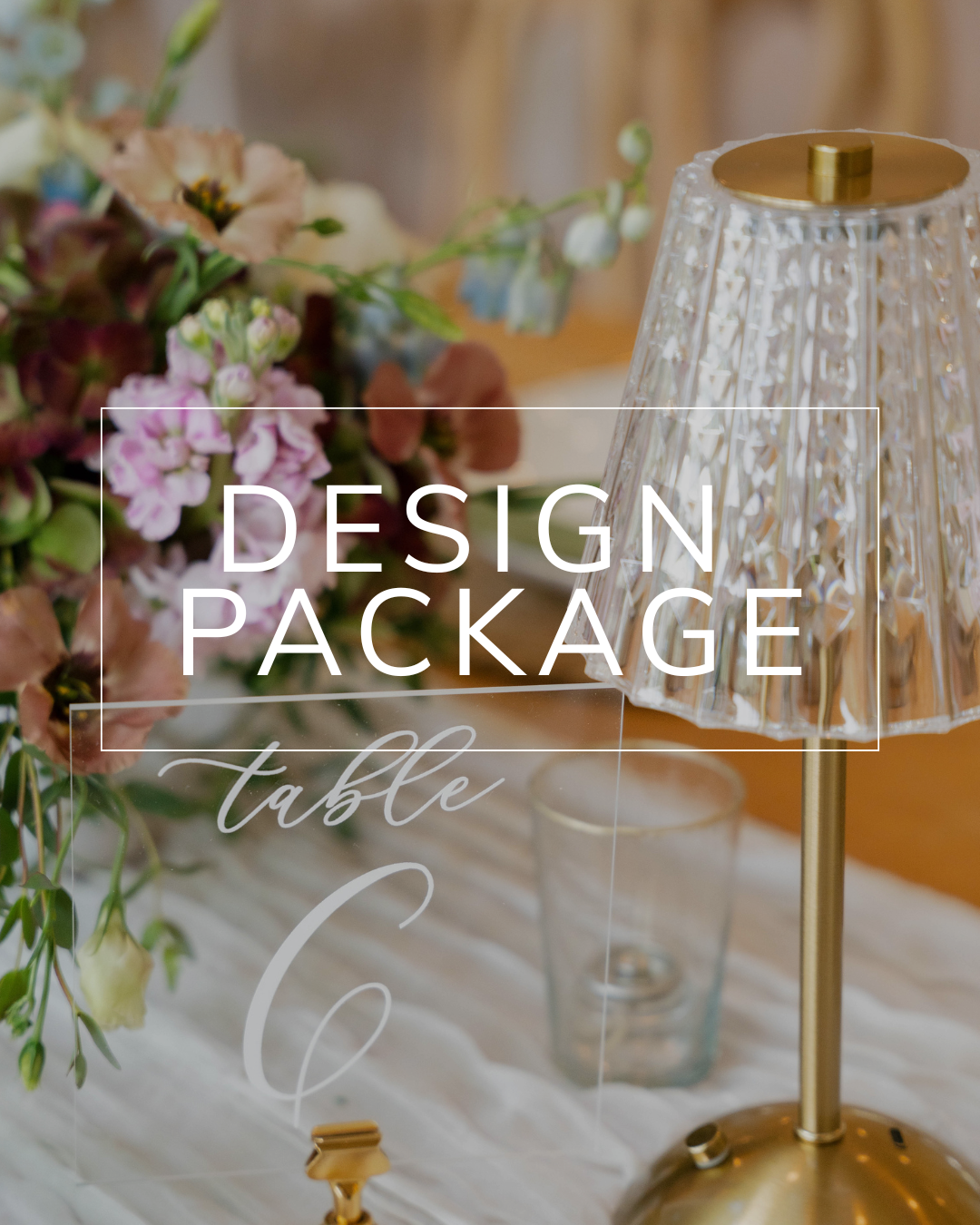 A table setting featuring a floral centerpiece, a modern glass lamp, and a clear sign reading