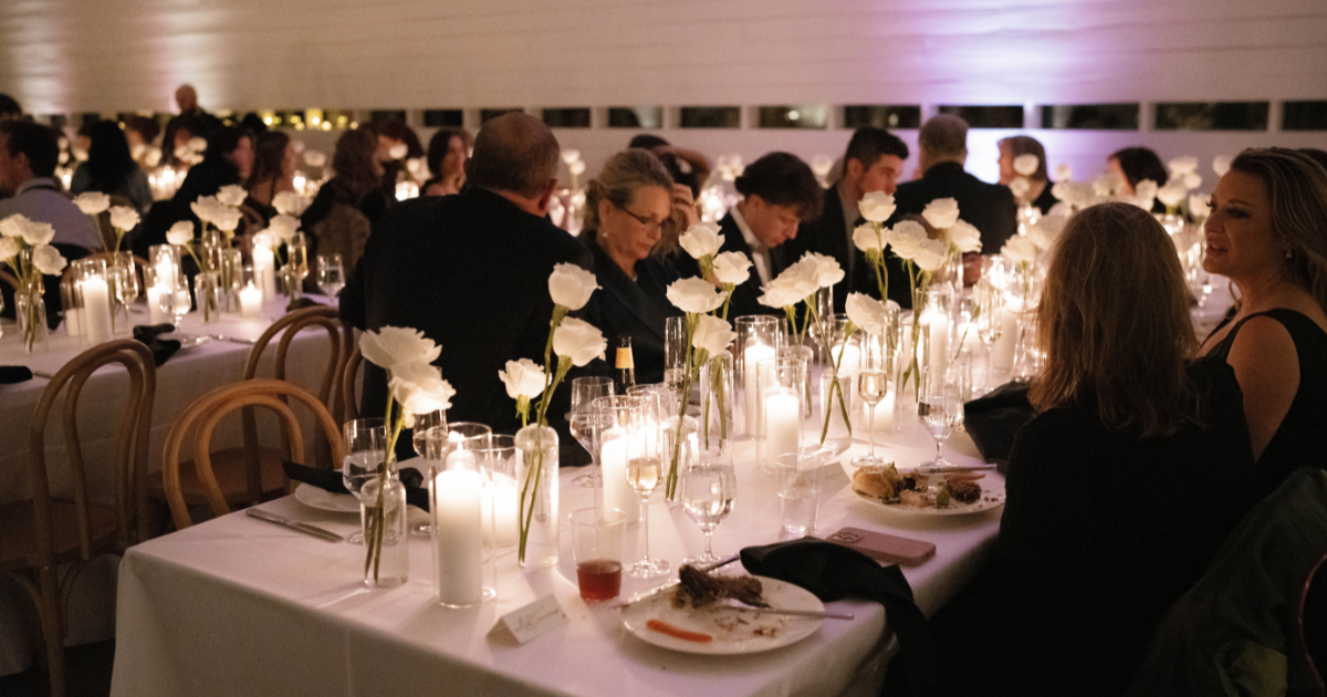 Elegant candlelit banquet with guests seated at long tables in a softly lit reception hall