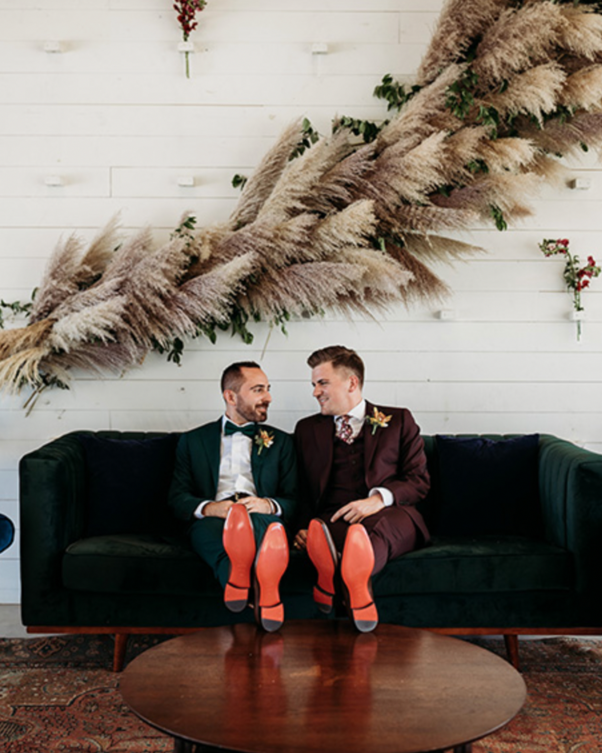 Two men in suits are sitting on a green couch.