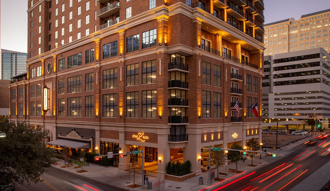 A large brick building that is up lit all around and is sitting on the corner of a city street.