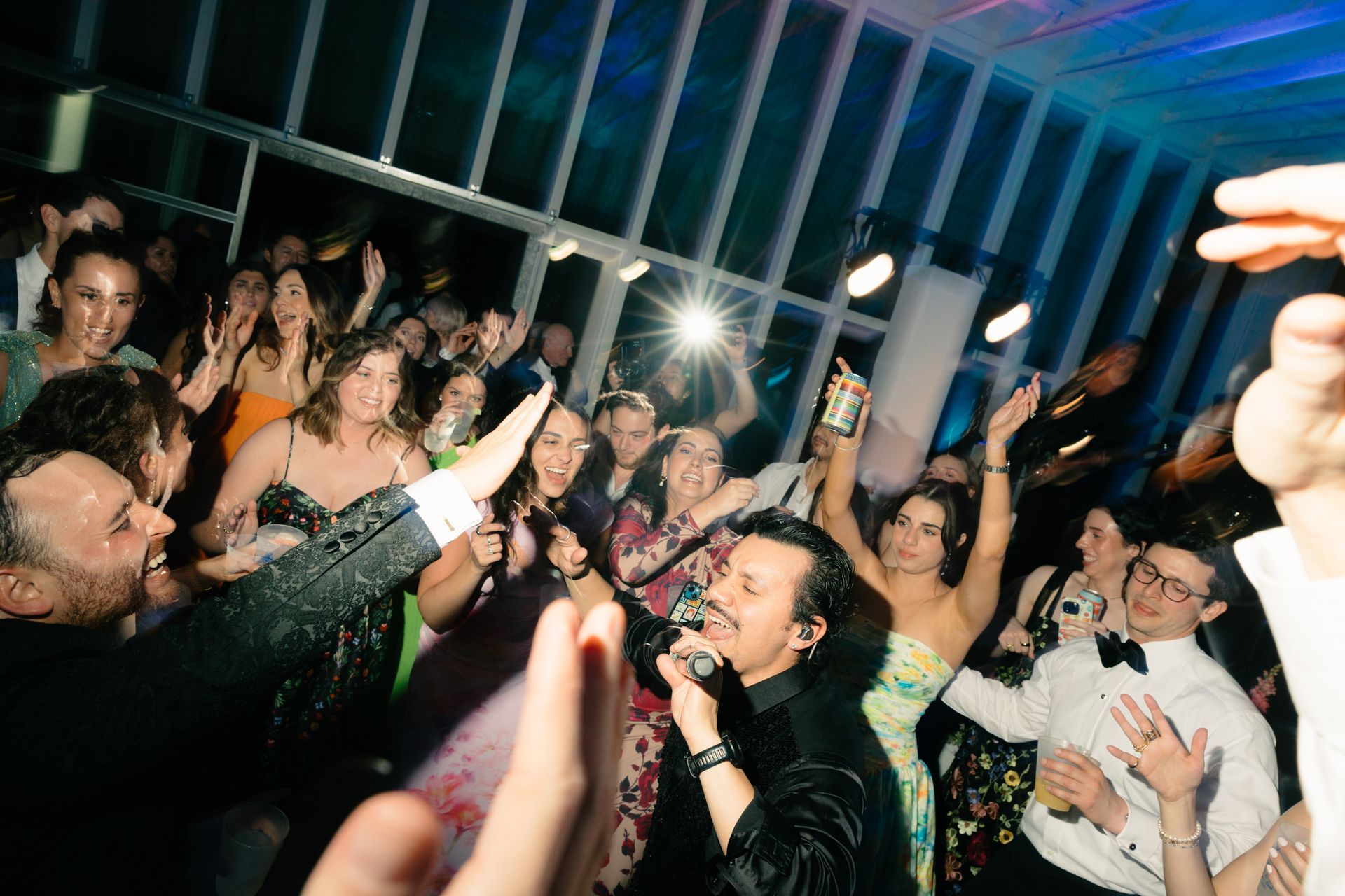 A crowded, dimly lit event space with a singer performing to an enthusiastic audience with raised hands.