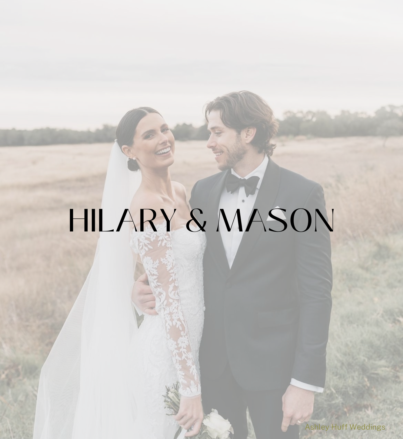A bride and groom in formal wedding attire stand smiling together in a soft-focus, grassy field.