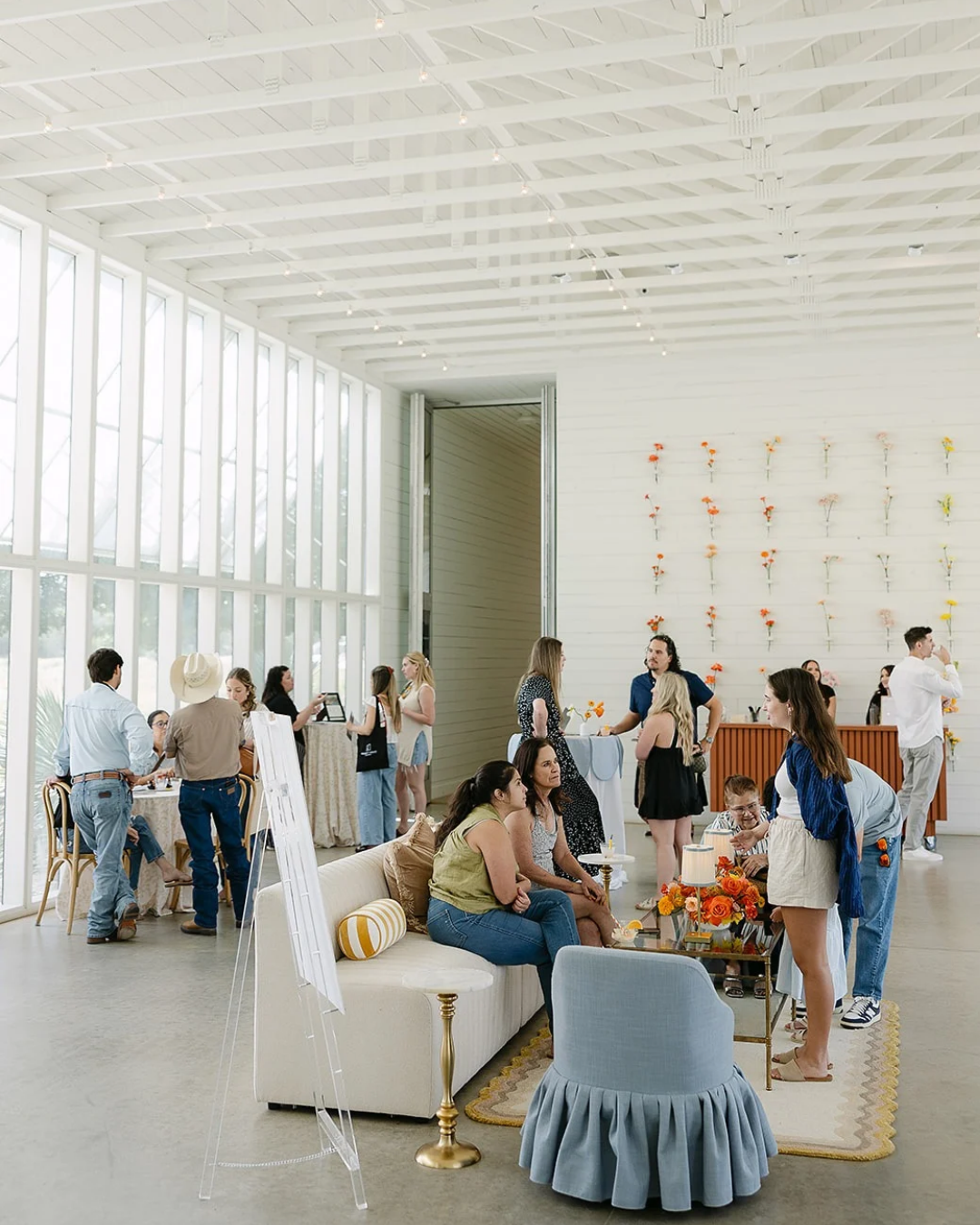 Bright gallery lounge with people mingling around white sofas and artwork on the walls