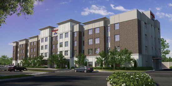 An artist 's impression of a Residence Inn hotel with groups of windows all around the brick exterior with cars parked in front of it.