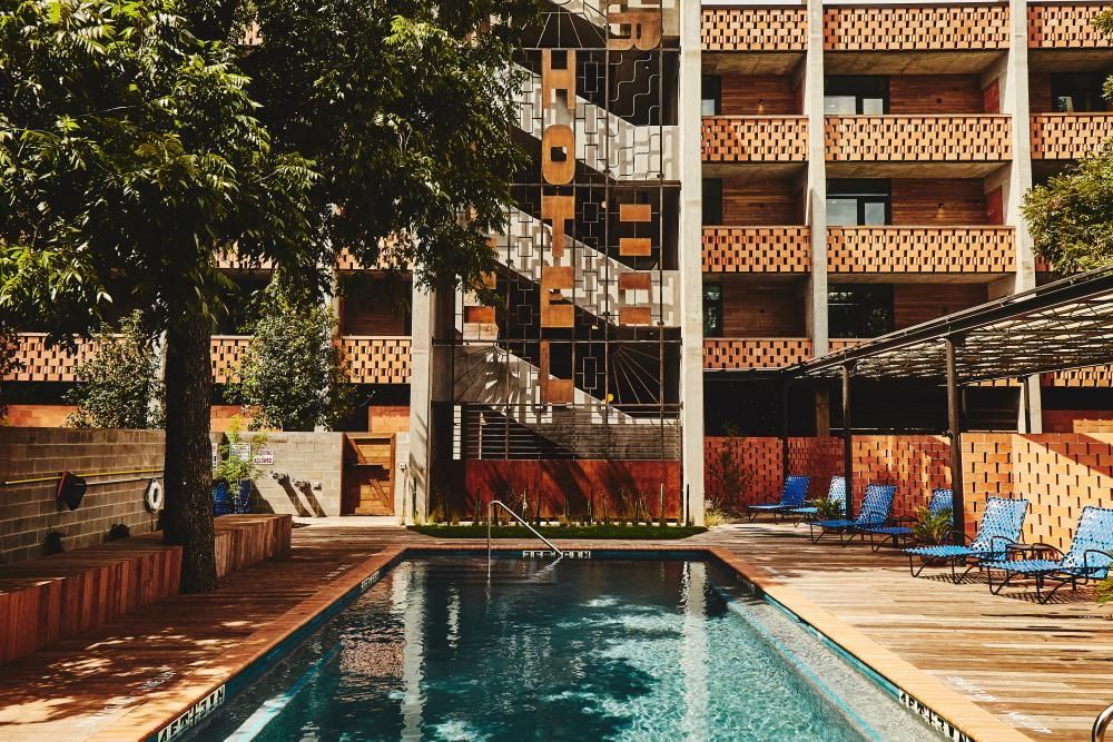A large swimming pool is in front of a brick building.