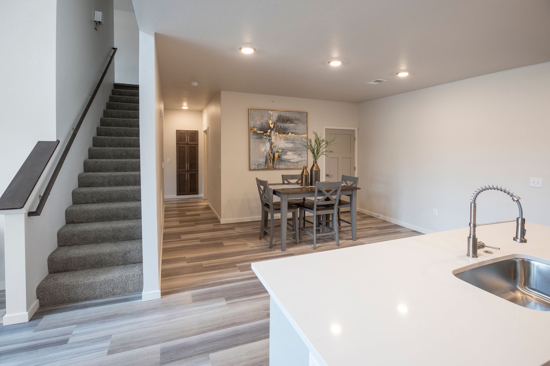 Open-concept home interior with staircase, dining table, and kitchen island with sink