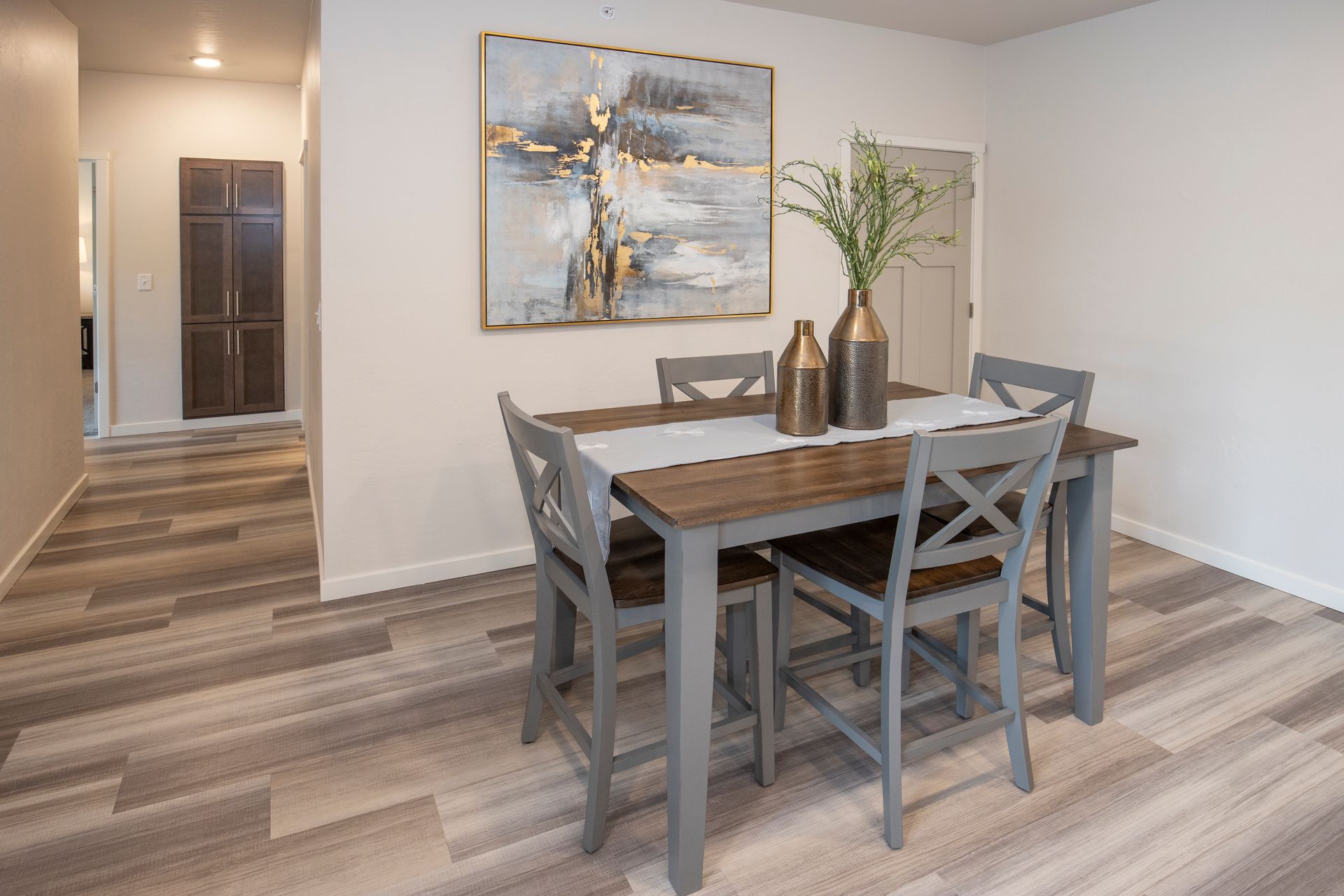 Modern dining room with gray table, chairs, wall art, and hallway beyond