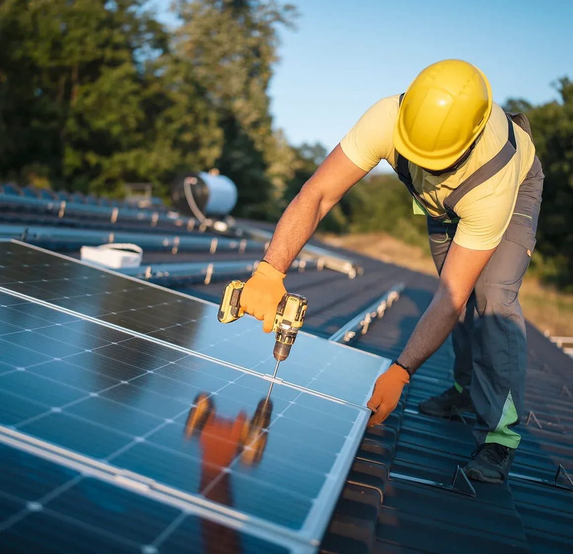 A Man Is Installing Solar Panels on A Roof with A Drill — Brent Hawe Solar & Electrical in Glenfield Park, NSW