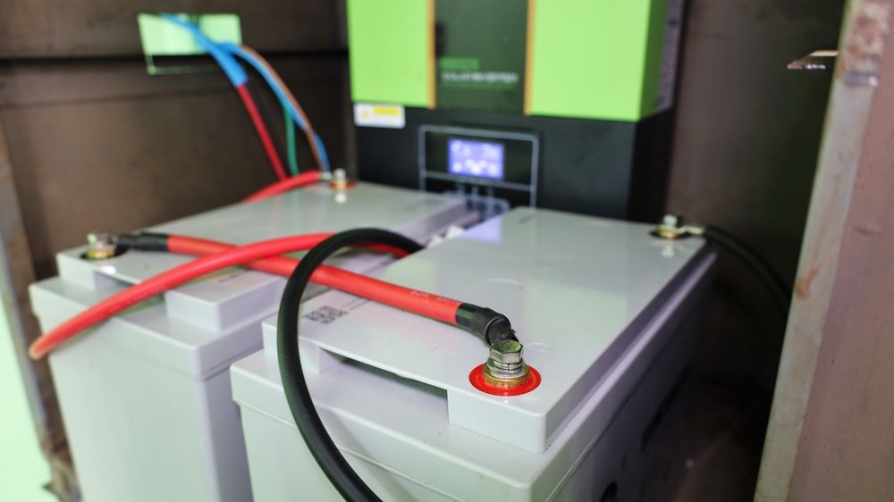 Two Batteries Are Connected to A Charger in A Room — Brent Hawe Solar & Electrical in Glenfield Park, NSW