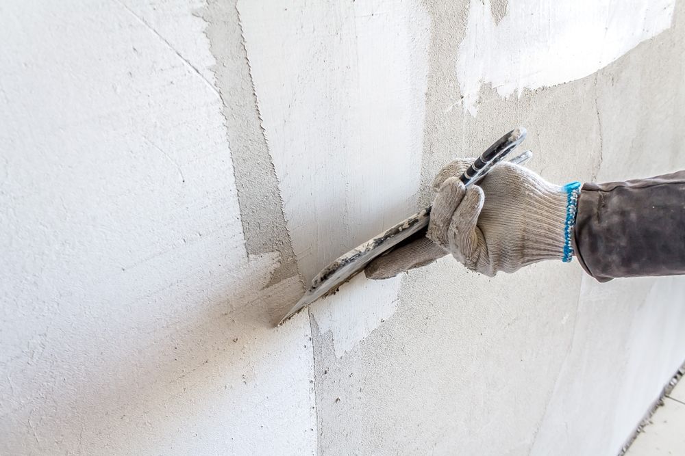 Hand with Trowel Smoothing Plaster on A White Wall in A Corner — Completely Plastered North Coast in Casino, NSW