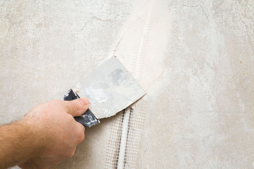 Hand with Putty Knife Smoothing Drywall Compound — Completely Plastered North Coast in Ballina, NSW