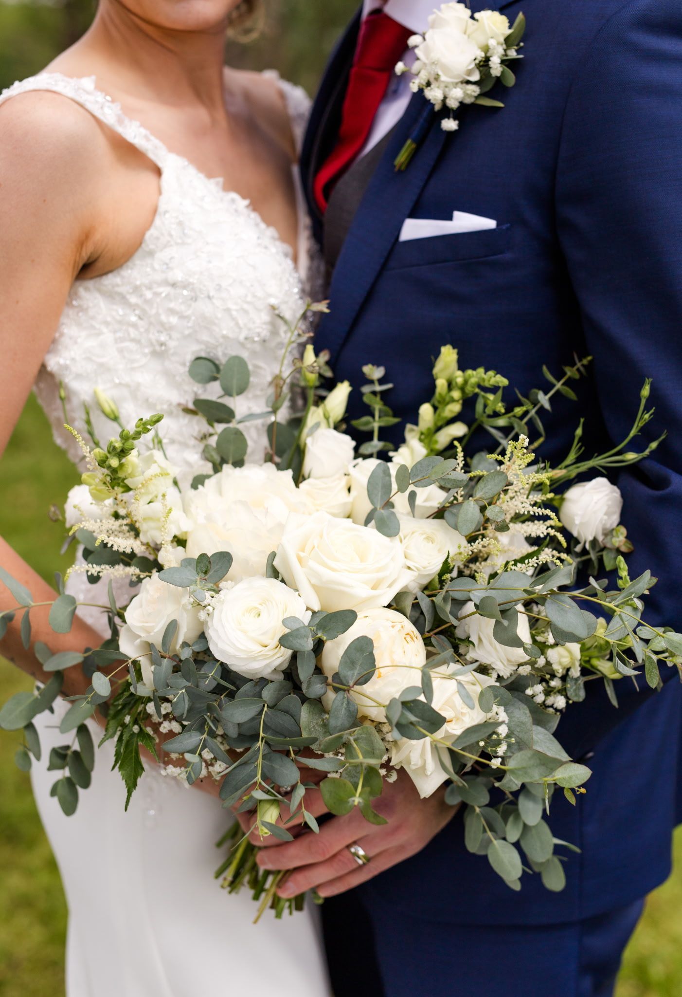 Bride and groom holding a large white floral bouquet at their wedding