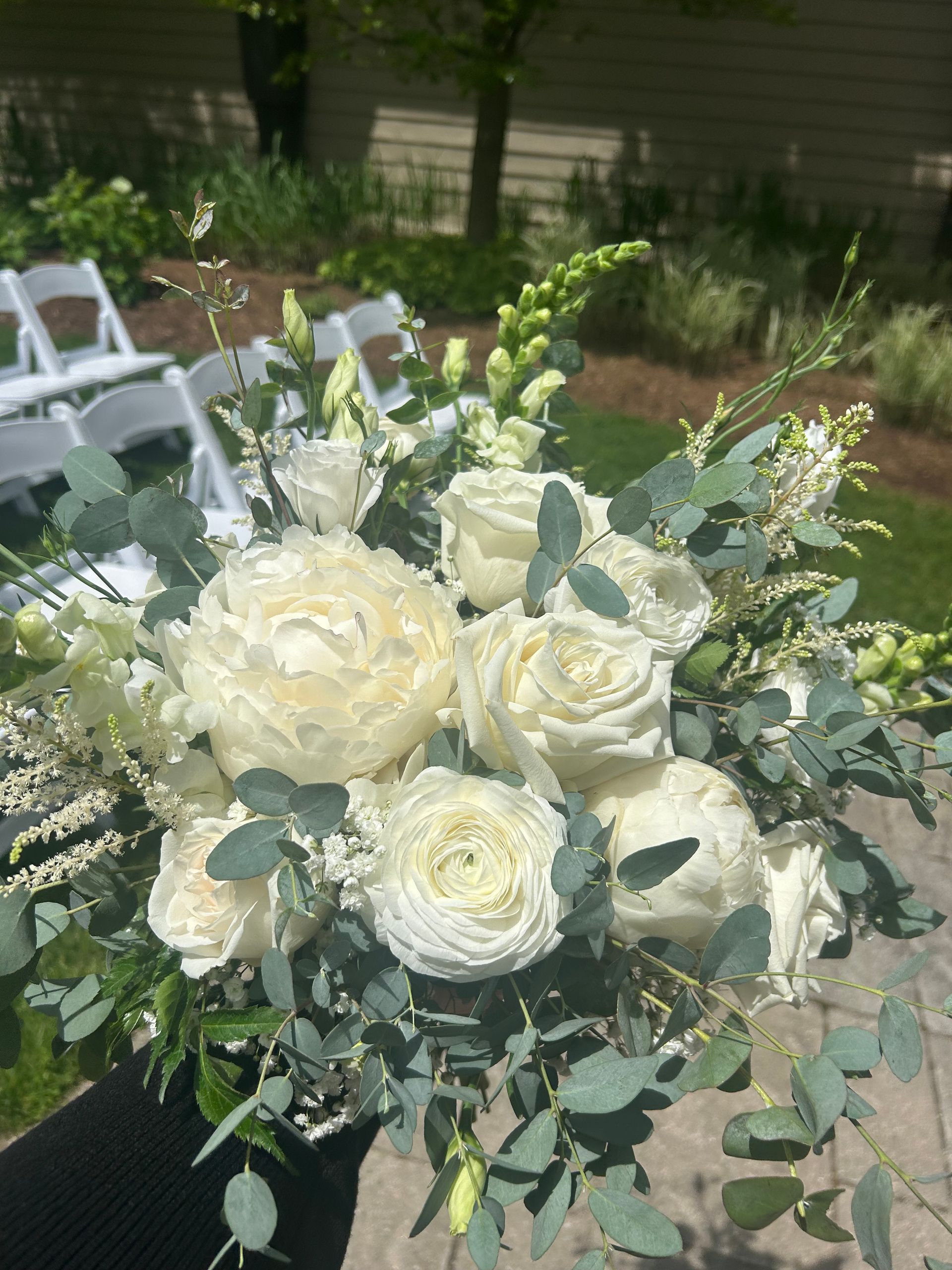 White rose bouquet with eucalyptus greenery on an outdoor table in a garden