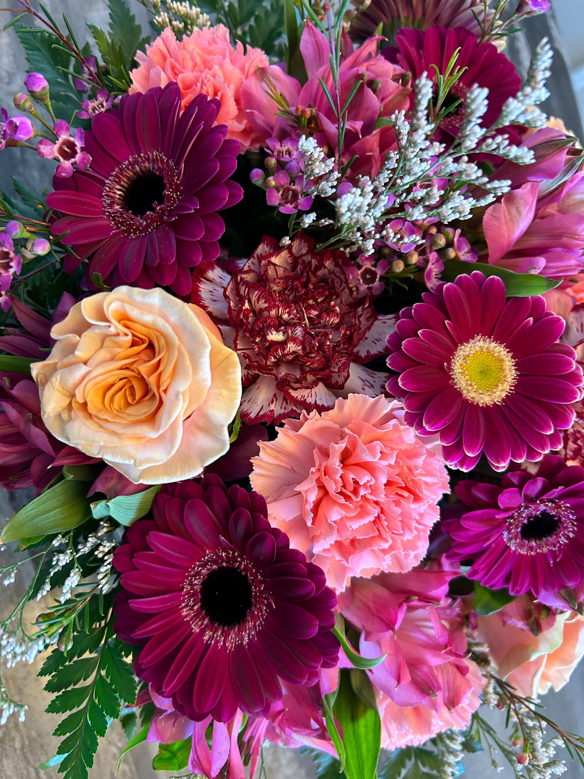 Mixed bouquet of pink, purple, and peach flowers with roses and daisies