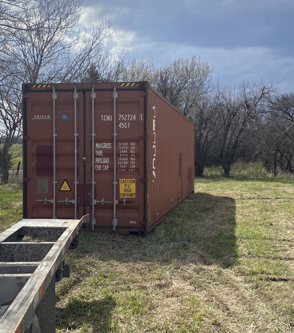 A large shipping container is parked in a grassy field.