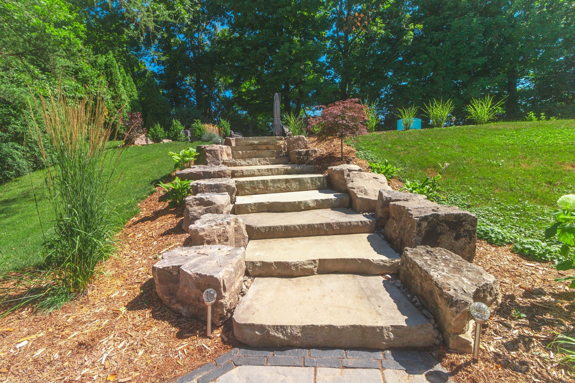 A set of stone stairs leading up to a grassy hill.
