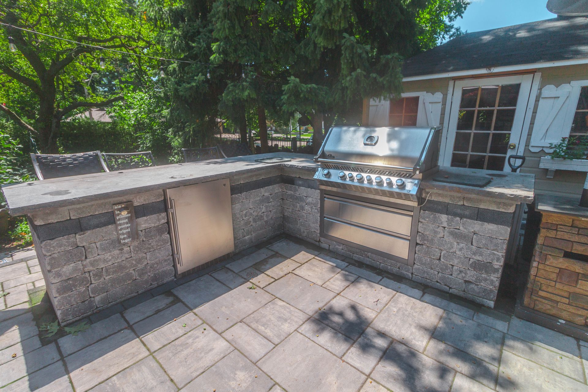 A large outdoor kitchen with a grill and a refrigerator.
