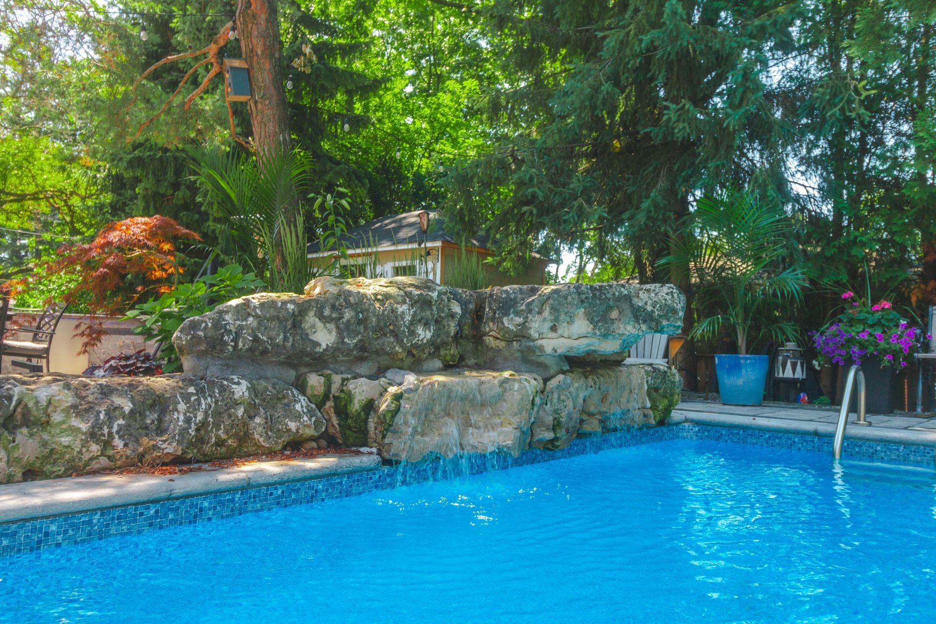 A large swimming pool with a waterfall in the backyard