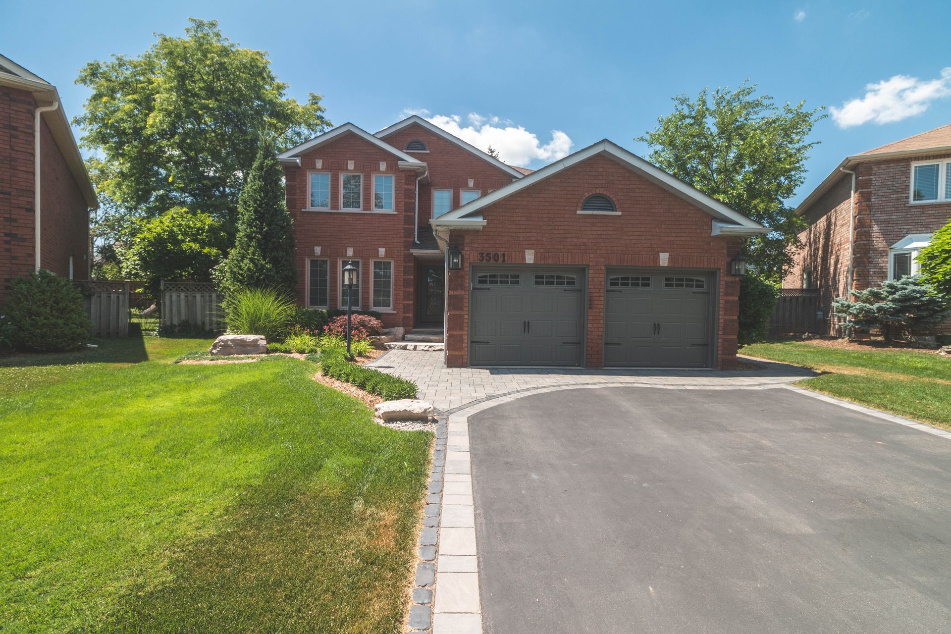 A brick house with two garage doors and a driveway