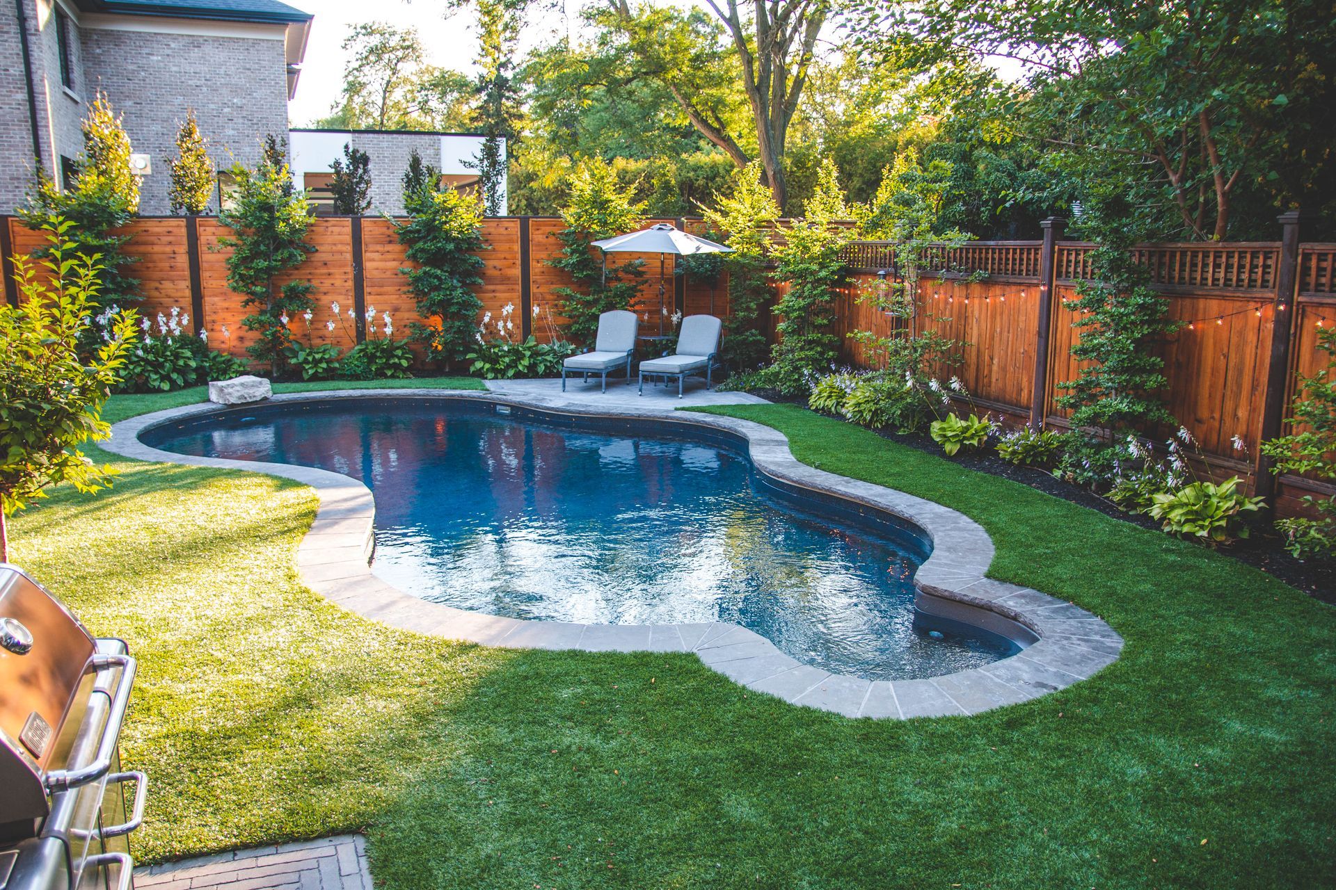 A large swimming pool in the middle of a lush green backyard