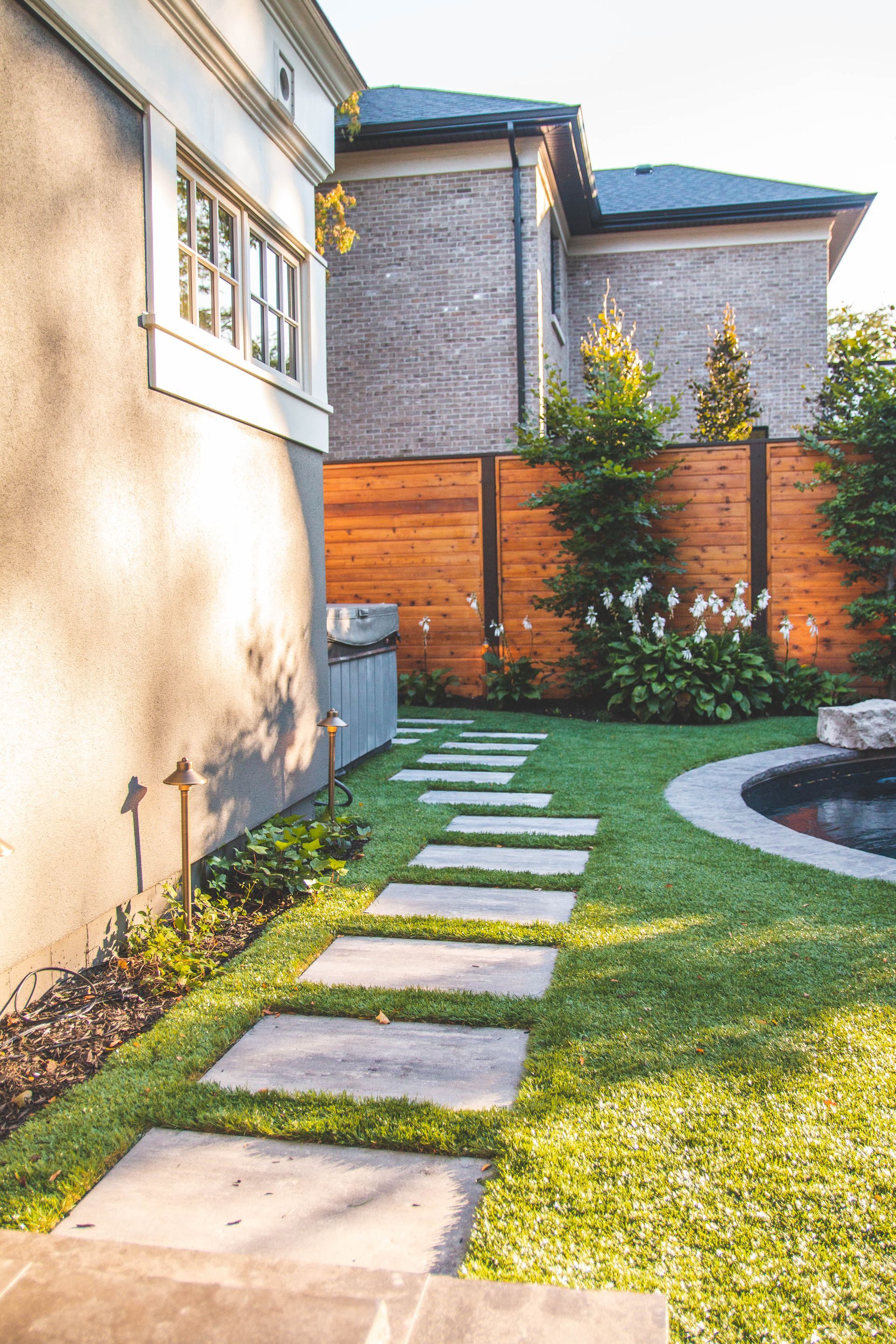 There is a walkway leading to a pool in the backyard of a house.