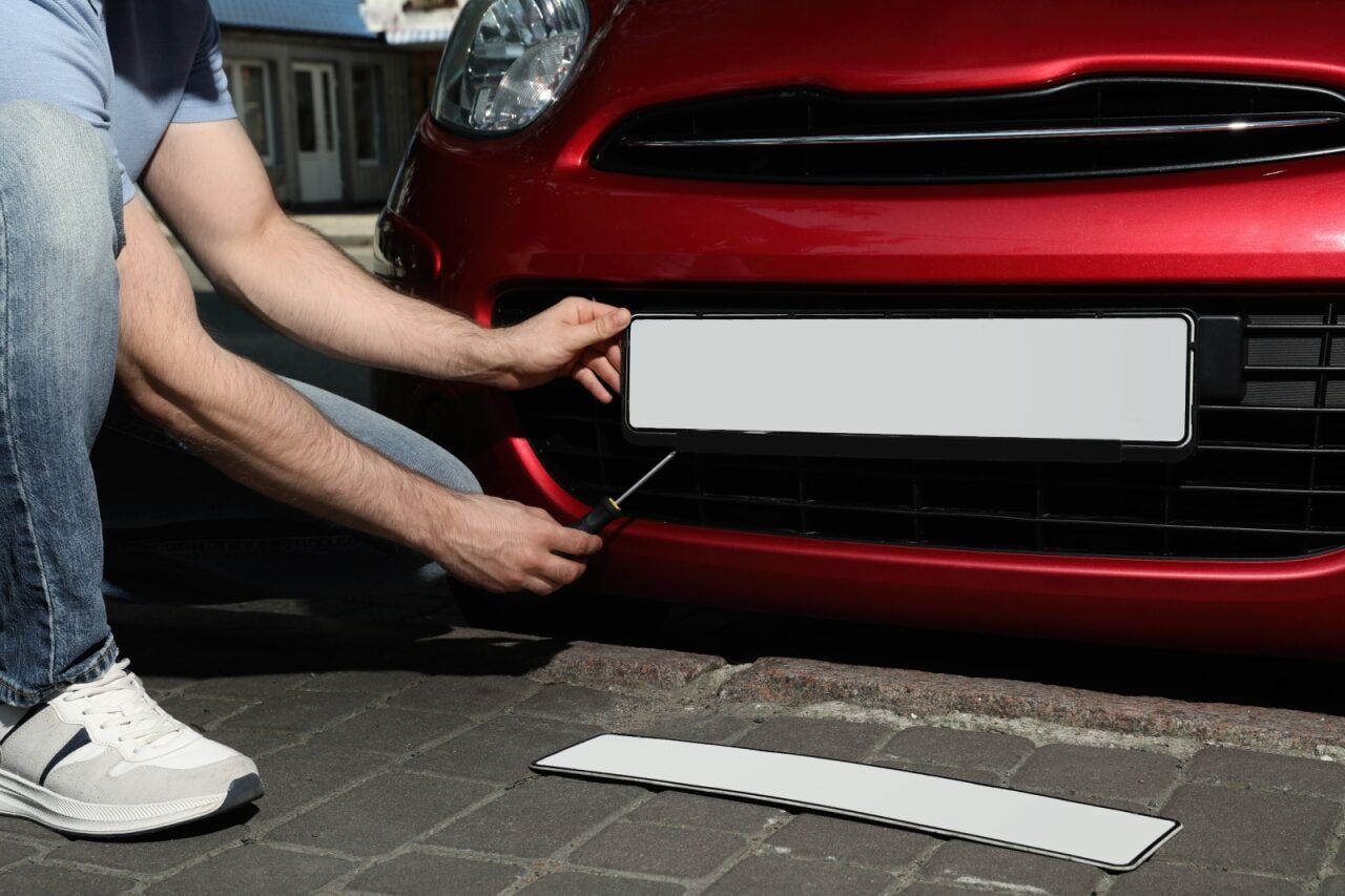 Person Attaching a White License Plate — The Automotive Den in Ballina, NSW