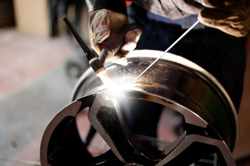 Person welding a shiny metal ring, with bright sparks in a workshop
