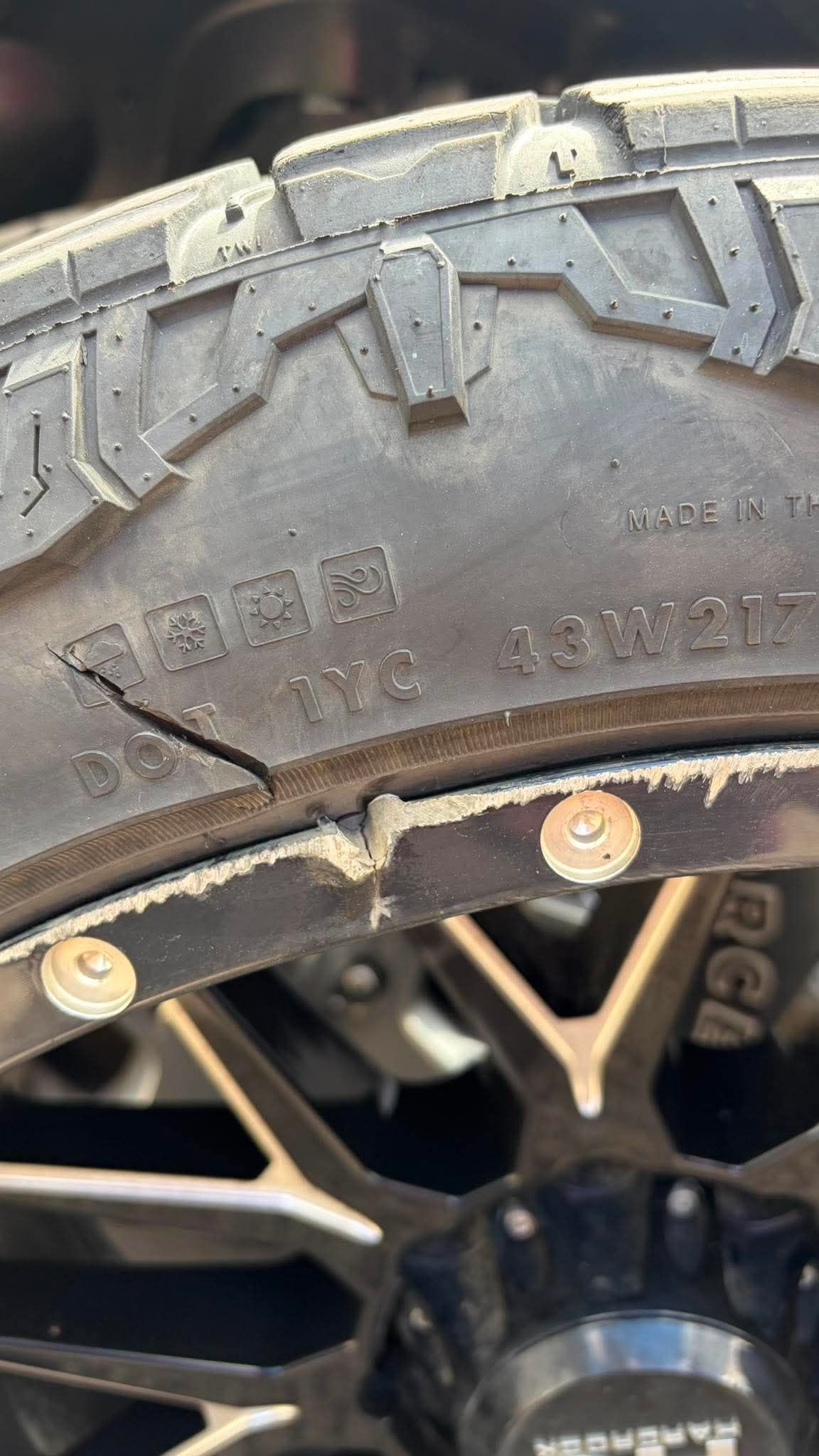 Close-up of an off-road tire mounted on a black wheel rim with gold bolts.