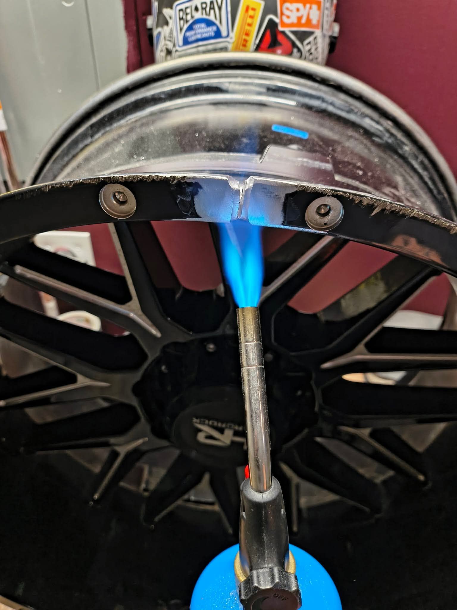 Blue flame heating a metal rod clamped to a wheel rim with a blowtorch