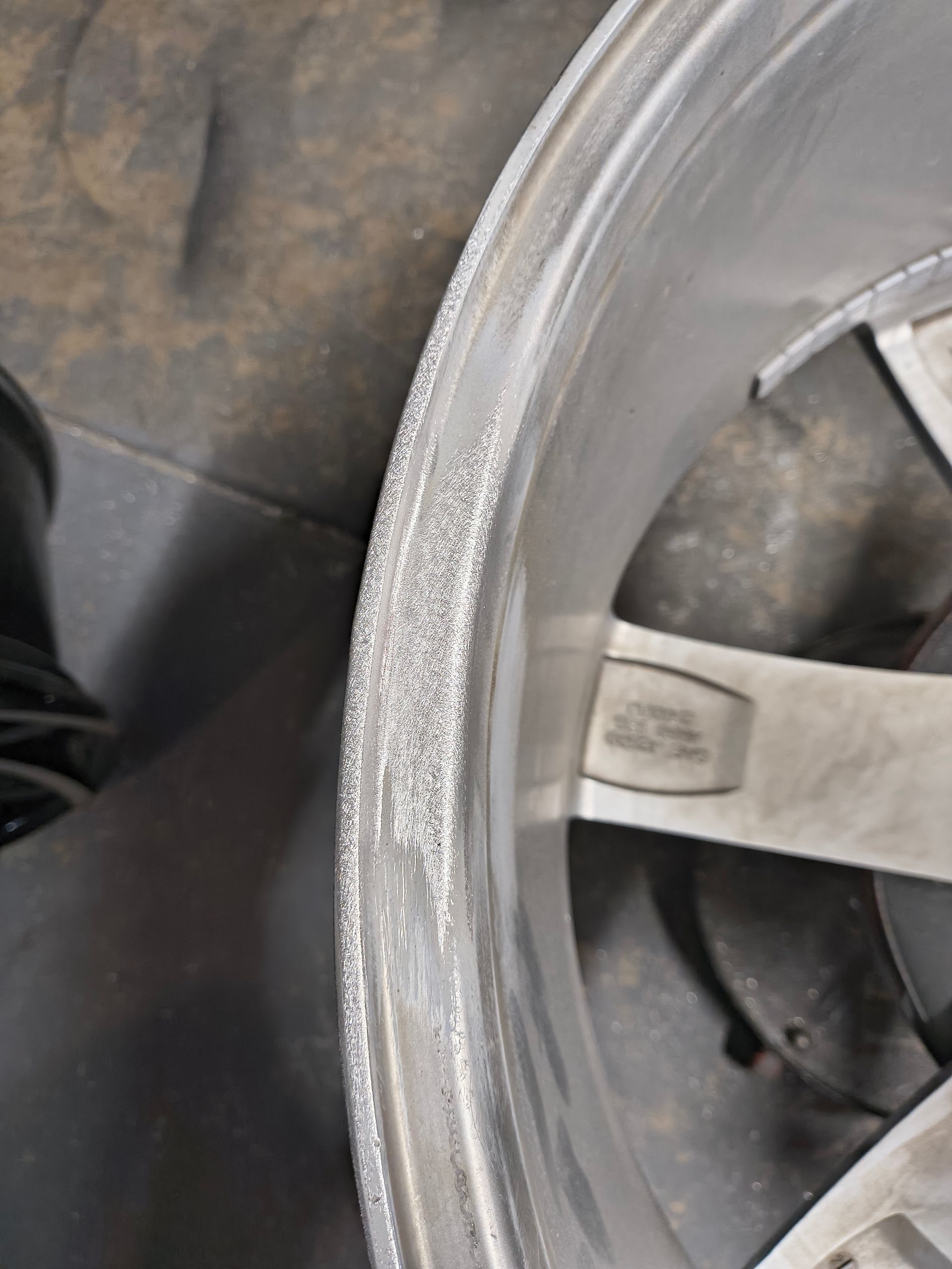 Close-up of a silver alloy wheel rim with a scratched edge on a car tire