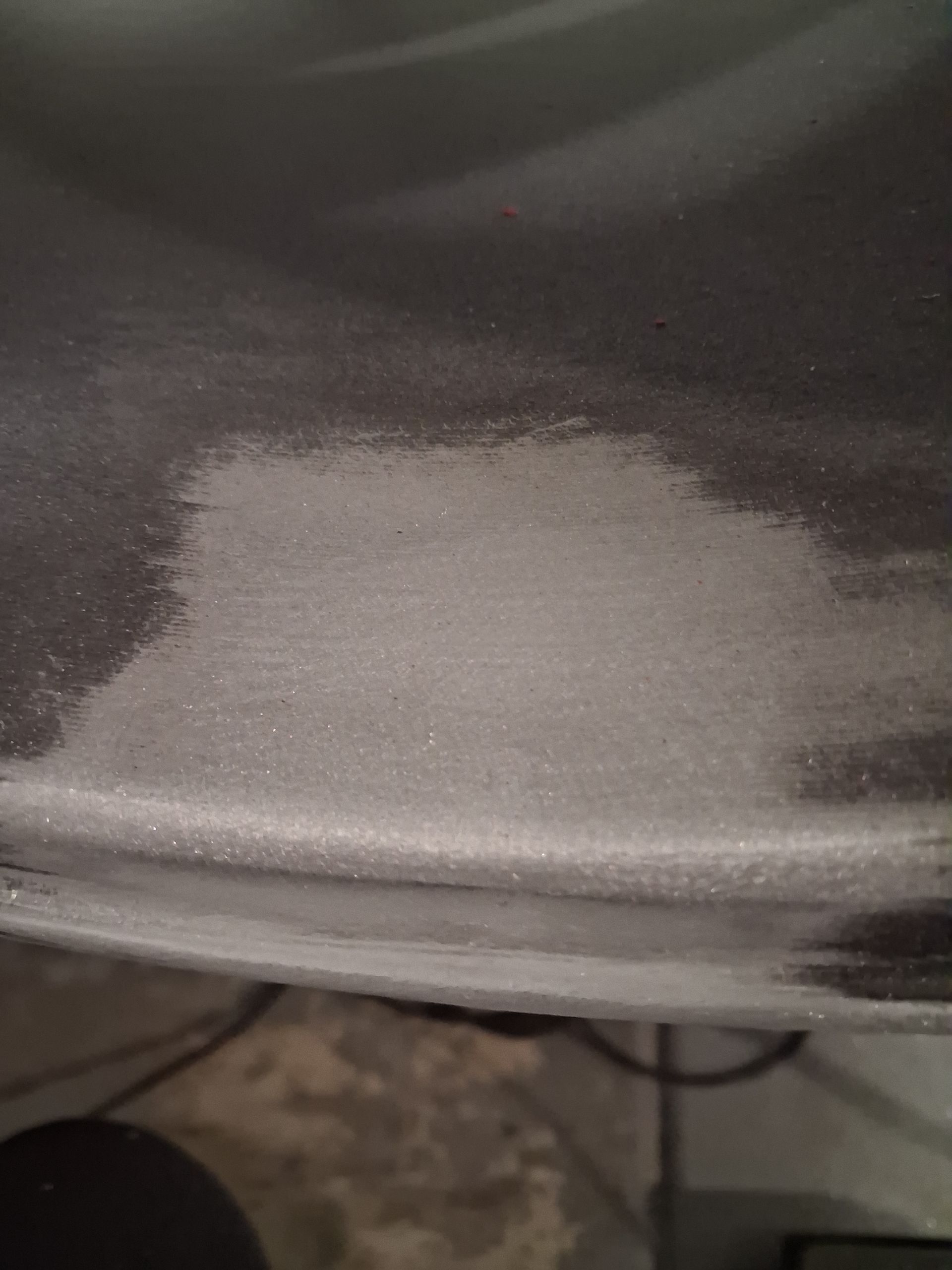 Close-up of a dusty black surface with a large light gray rectangular patch.
