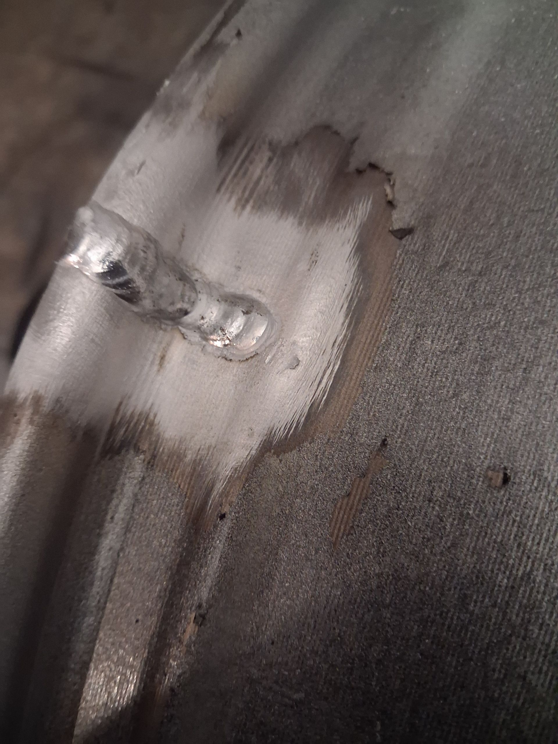 Close-up of a gray fabric surface with a white stain and a small torn spot
