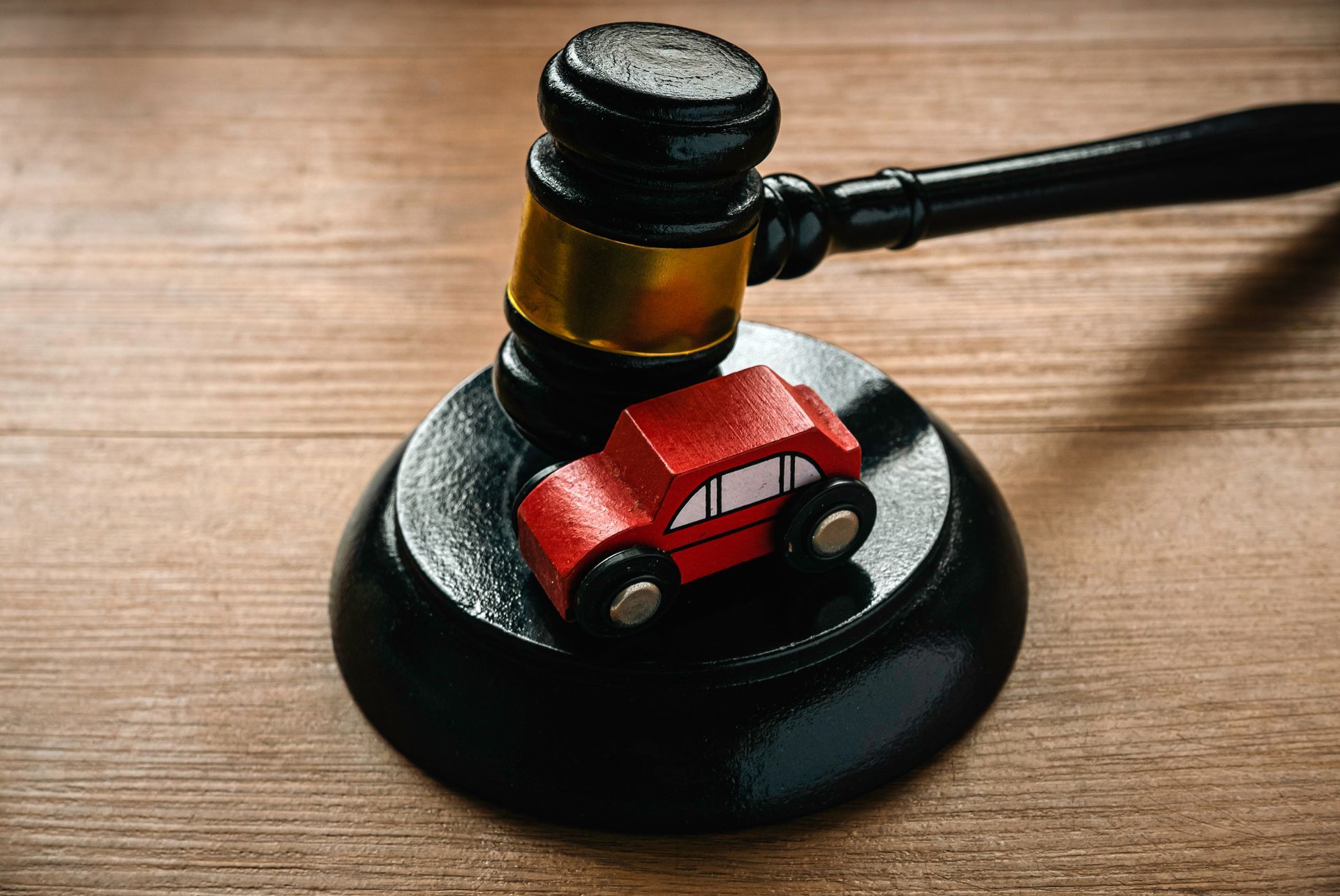A wooden gavel with a toy car on top of it on a wooden table.