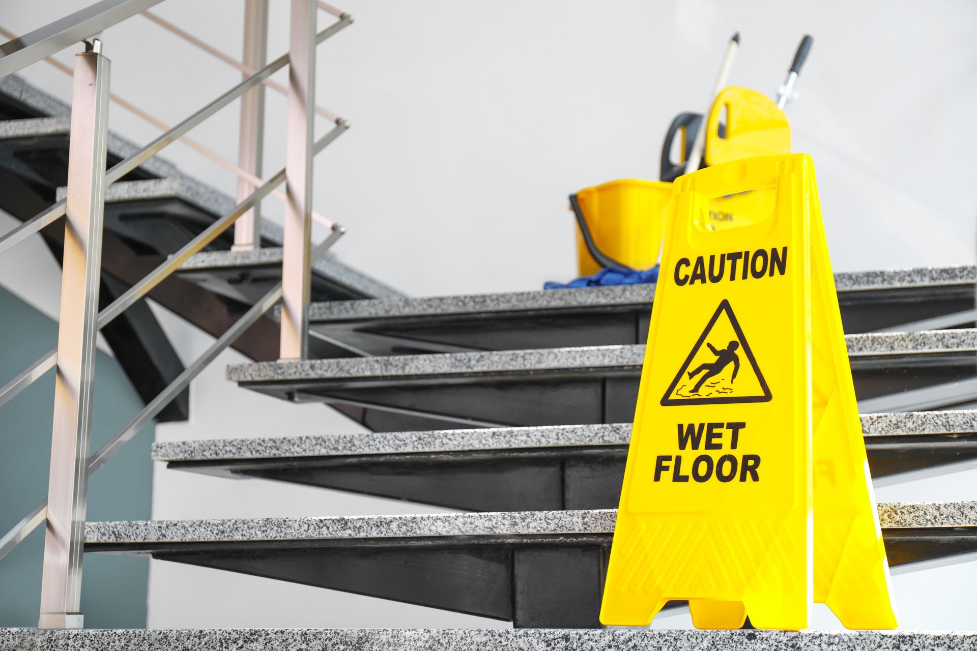 A yellow wet floor sign is sitting on top of a set of stairs.