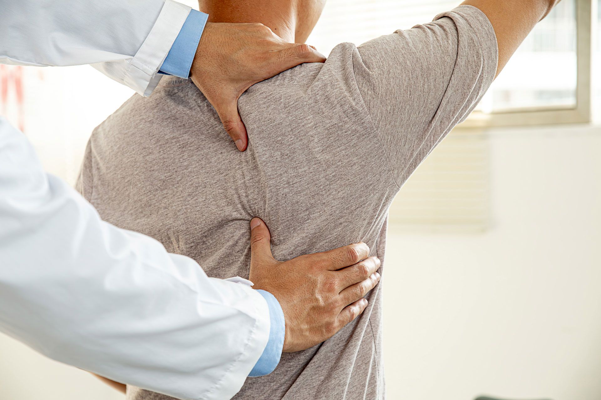 Doctor examining a patient's back and shoulder.