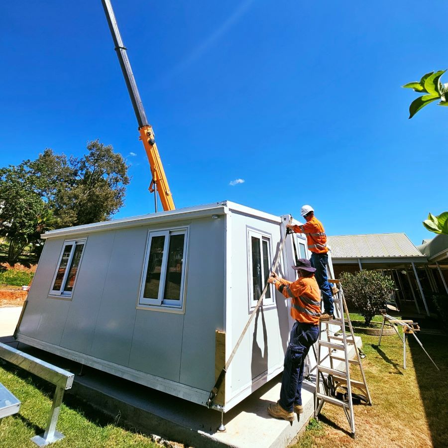 Two Men Are Working on a House With a Crane in the Background — Pro-Jax Pty Ltd in Ingham, QLD