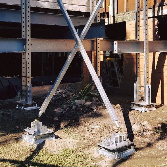 A Metal Structure is Being Built Next to a Brick Building  — Pro-Jax Pty Ltd in Julia Creek, QLD