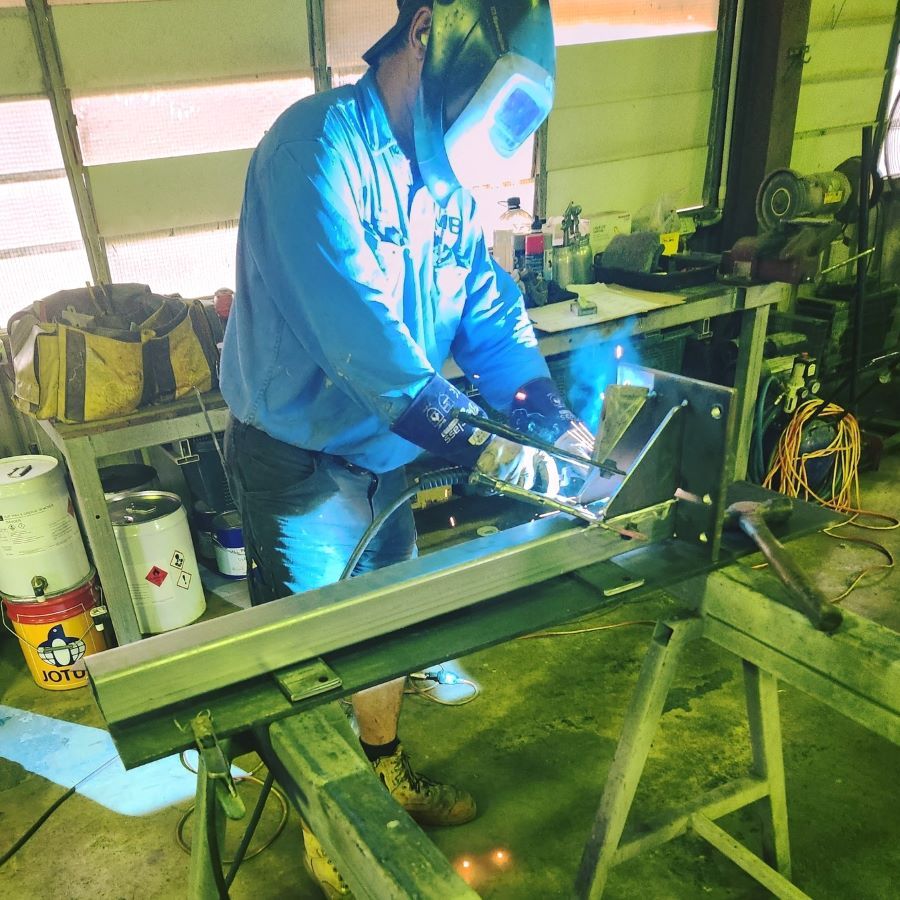 A Man Wearing a Welding Mask is Working on a Piece of Metal — Pro-Jax Pty Ltd in Ingham, QLD