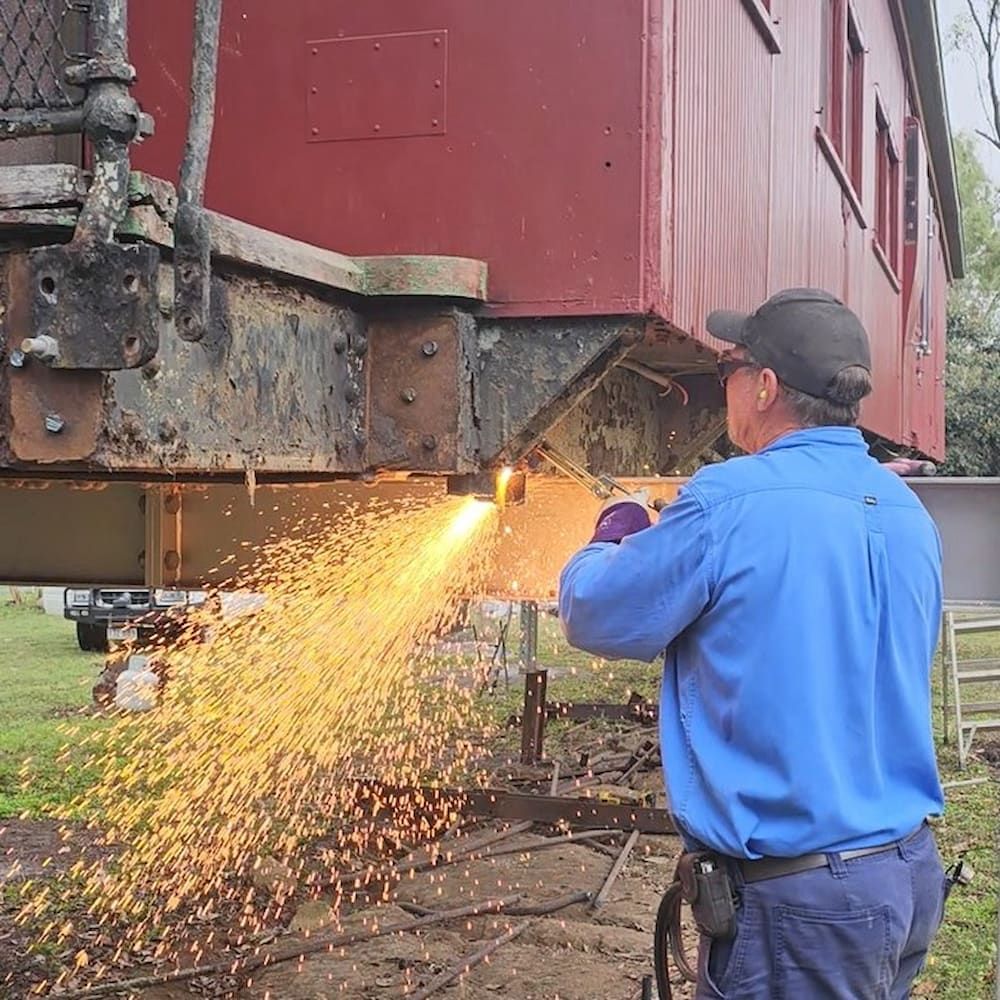 Man Using a Torch to Cut Metal on a Red Train Car — Pro-Jax Pty Ltd in Bohle, QLD