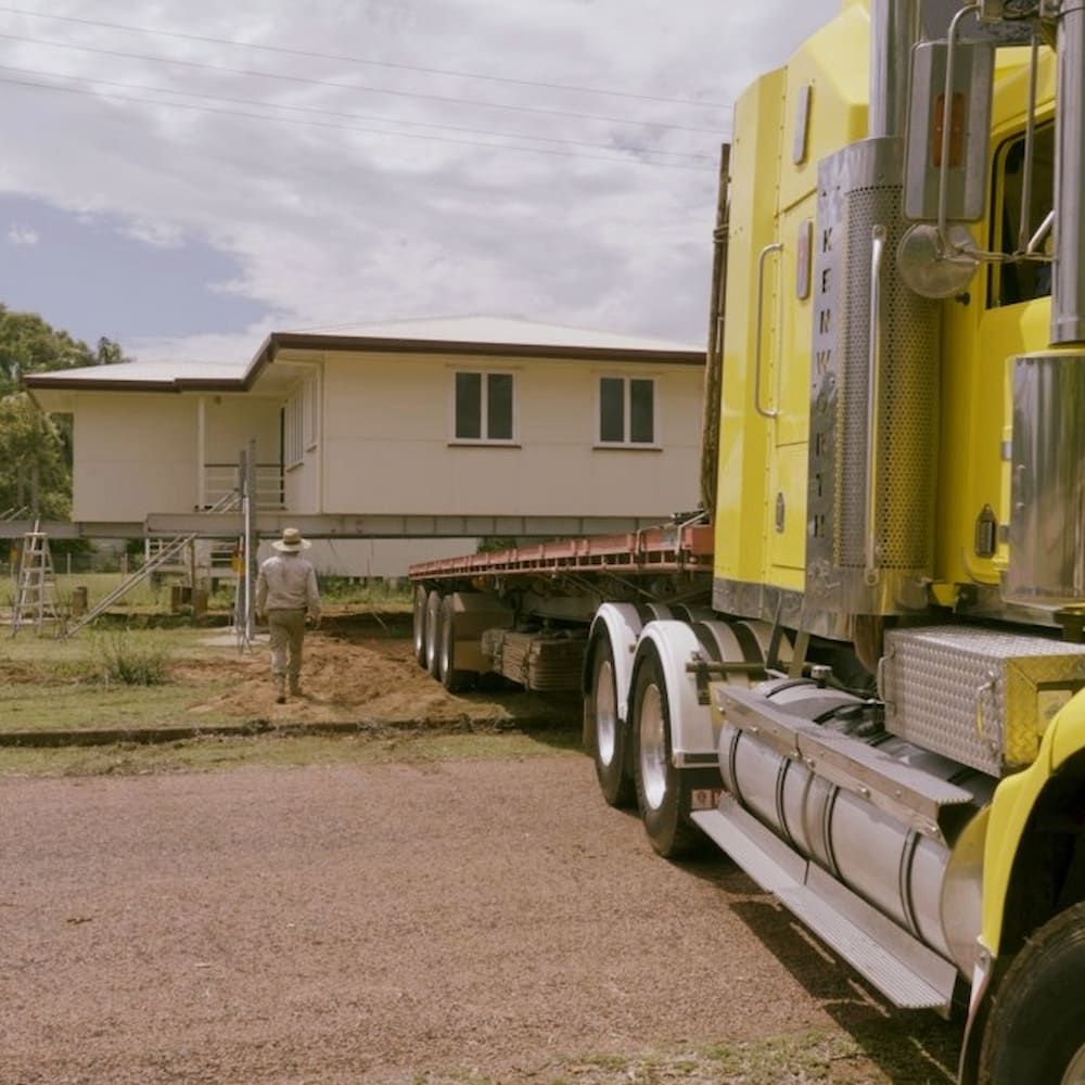 Yellow Semi-truck Transporting a White House on a Flatbed Trailer — Pro-Jax Pty Ltd in Bowen, QLD