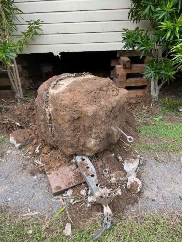 A Large Rock is Sitting in the Dirt in Front of a House — Pro-Jax Pty Ltd in Mackay, QLD