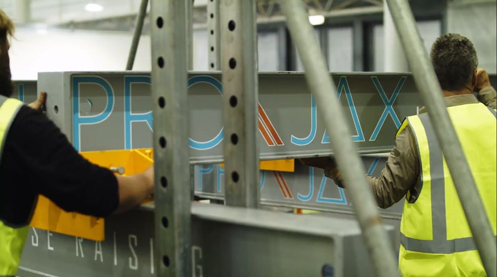 Two Workers in Safety Vests Assemble Signage Using Scaffolding — Pro-Jax Pty Ltd in Bowen, QLD