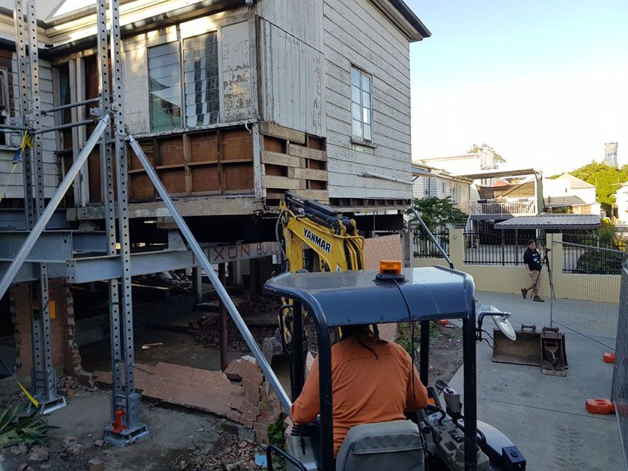 A Man is Driving a Small Excavator in Front of a House Under Construction  — Pro-Jax Pty Ltd in Hughenden, QLD